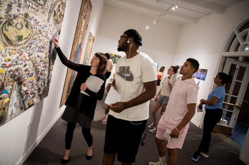 Collections manager and exhibitions coordinator Christa Story points out specific details on a piece of art to students at the 